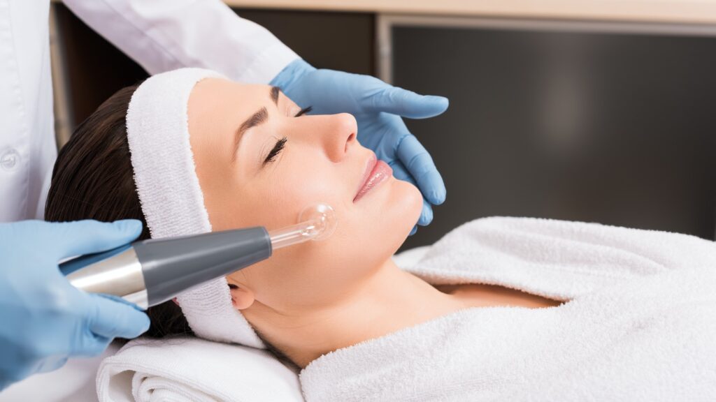 beautician making darsonvalization to woman at beauty salon